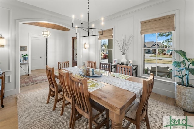 dining area featuring arched walkways, light wood-style flooring, and baseboards