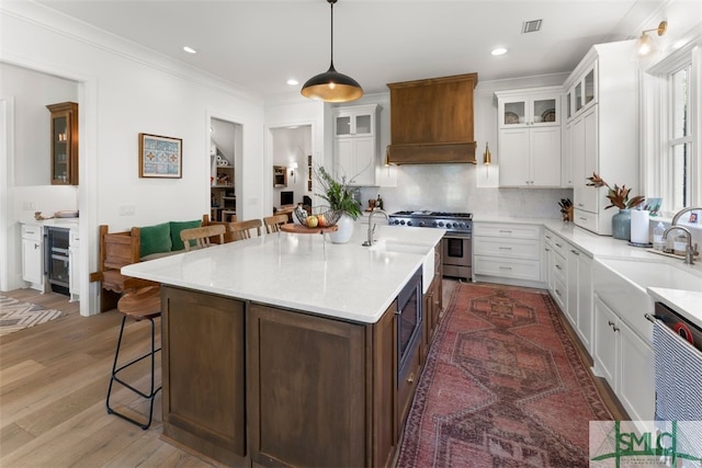 kitchen featuring a sink, high end stove, custom exhaust hood, and a breakfast bar area