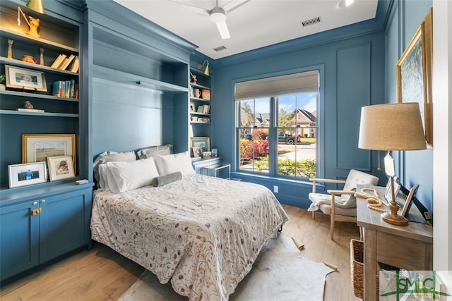 bedroom featuring light wood finished floors, visible vents, and a ceiling fan