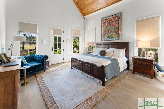 bedroom featuring light wood finished floors, multiple windows, high vaulted ceiling, and access to outside