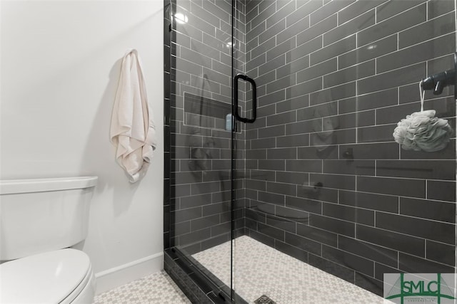 bathroom with tile patterned flooring, a shower stall, toilet, and baseboards