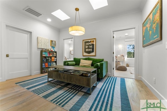 living room with wood finished floors, baseboards, visible vents, a skylight, and ornamental molding