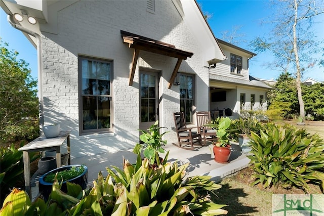 rear view of property featuring brick siding and a patio