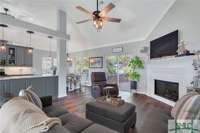 living room with a glass covered fireplace, visible vents, crown molding, and dark wood-type flooring