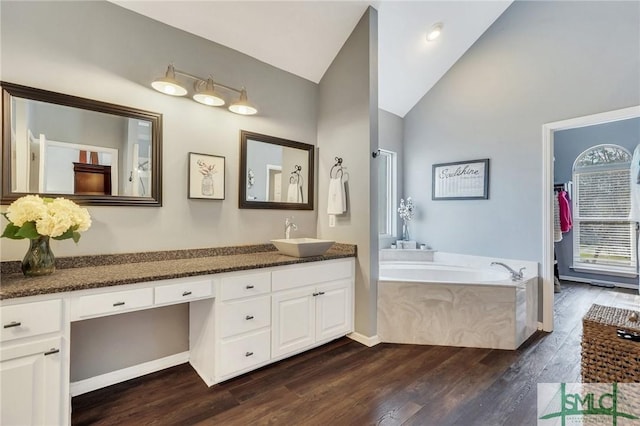 bathroom with vanity, vaulted ceiling, a garden tub, and wood finished floors