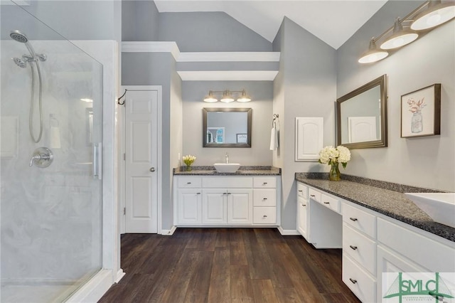 bathroom with a shower stall, lofted ceiling, two vanities, wood finished floors, and a sink