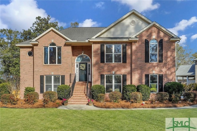 raised ranch featuring brick siding and a front lawn