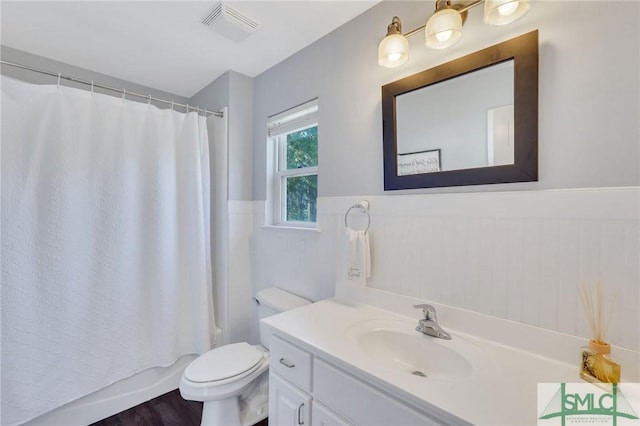 full bathroom with vanity, a wainscoted wall, visible vents, shower / bath combination with curtain, and toilet