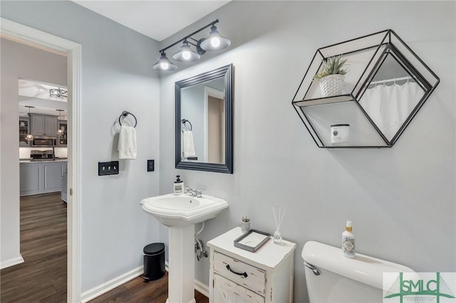 bathroom with a sink, baseboards, toilet, and wood finished floors