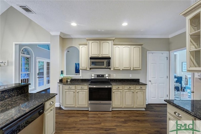 kitchen featuring visible vents, cream cabinetry, appliances with stainless steel finishes, and dark wood-style flooring