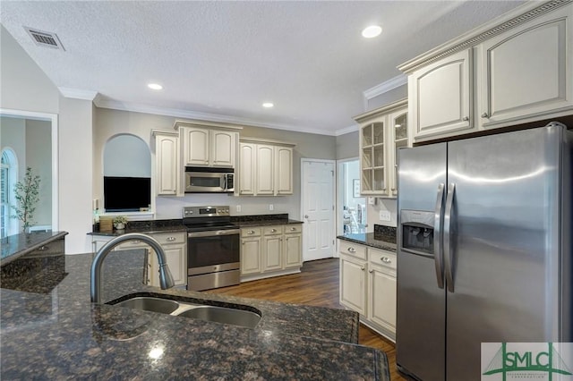 kitchen with appliances with stainless steel finishes, cream cabinets, and a sink