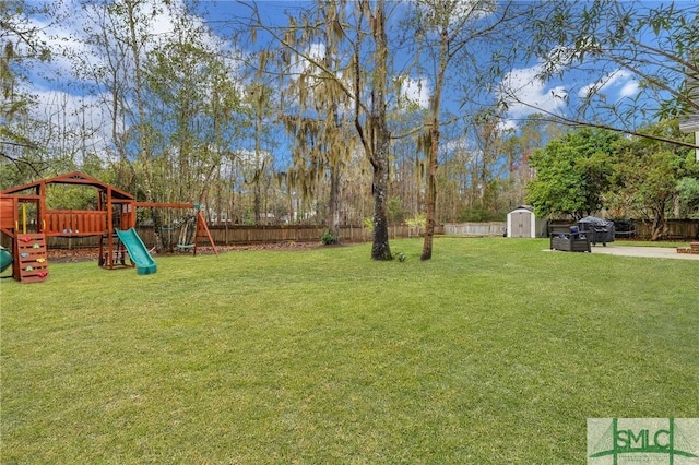 view of yard with a storage shed, a playground, an outbuilding, and a fenced backyard