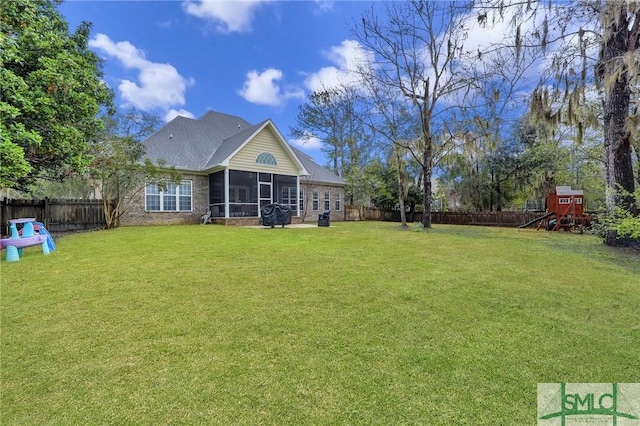 view of yard with a sunroom, a fenced backyard, and a playground