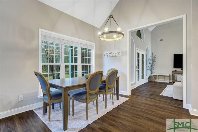 dining area featuring baseboards, wood finished floors, high vaulted ceiling, and a chandelier