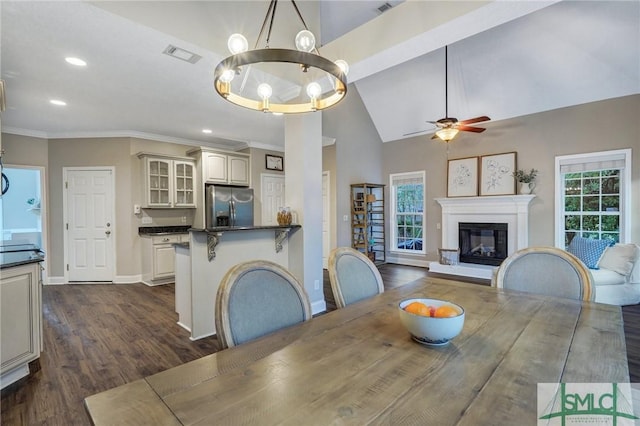 dining area featuring visible vents, dark wood-type flooring, a healthy amount of sunlight, and a glass covered fireplace