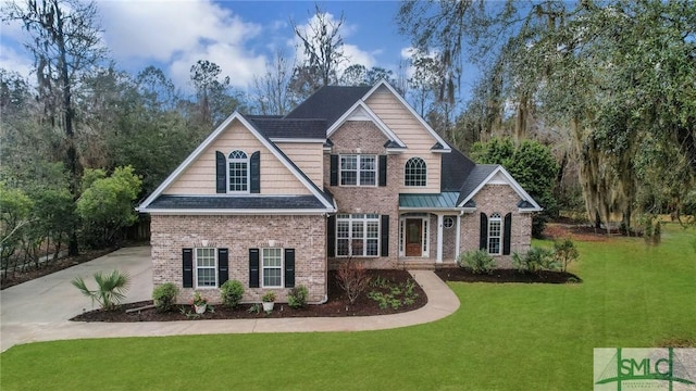 craftsman-style home with brick siding, concrete driveway, a front yard, and a standing seam roof