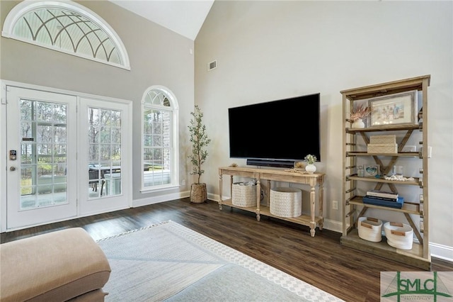 living area with visible vents, baseboards, high vaulted ceiling, and wood finished floors