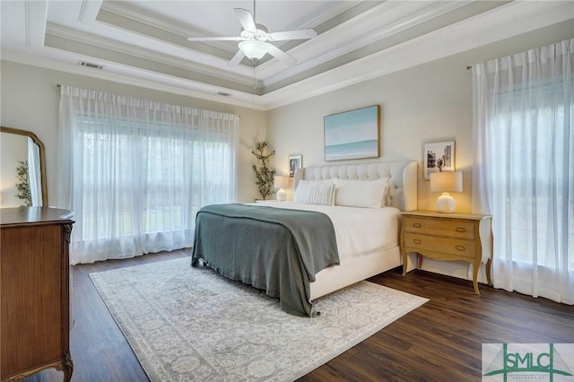 bedroom featuring dark wood finished floors, visible vents, crown molding, and a raised ceiling