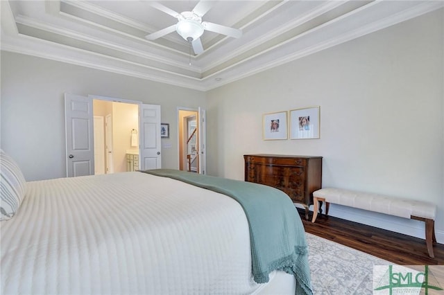 bedroom with a ceiling fan, wood finished floors, crown molding, ensuite bathroom, and a raised ceiling