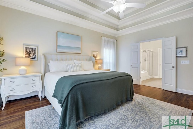 bedroom featuring connected bathroom, a tray ceiling, wood finished floors, and crown molding