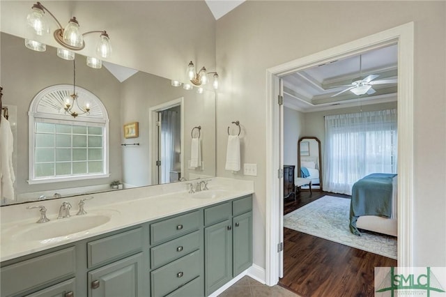 full bath with ensuite bath, ceiling fan with notable chandelier, a tray ceiling, and a sink