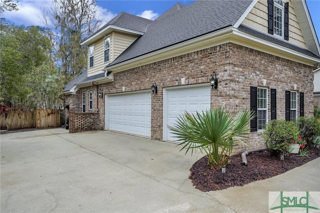 view of side of property with brick siding, concrete driveway, and fence