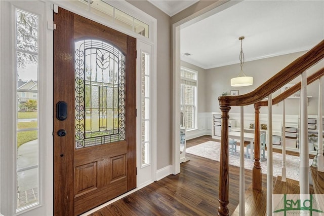 foyer entrance with dark wood-type flooring, stairway, a decorative wall, wainscoting, and crown molding