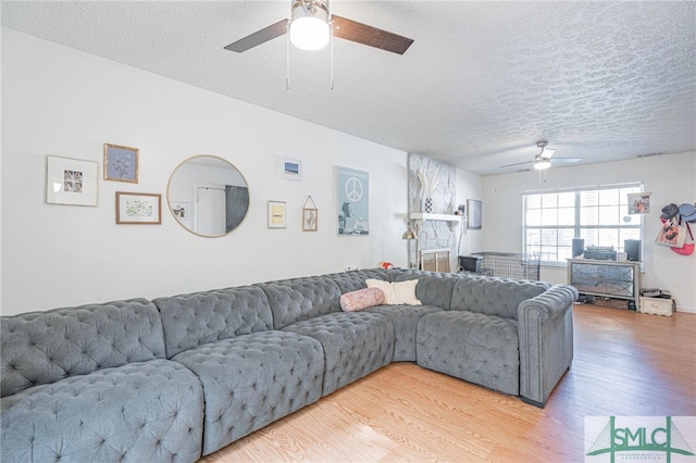 living room featuring a textured ceiling, ceiling fan, and light wood finished floors