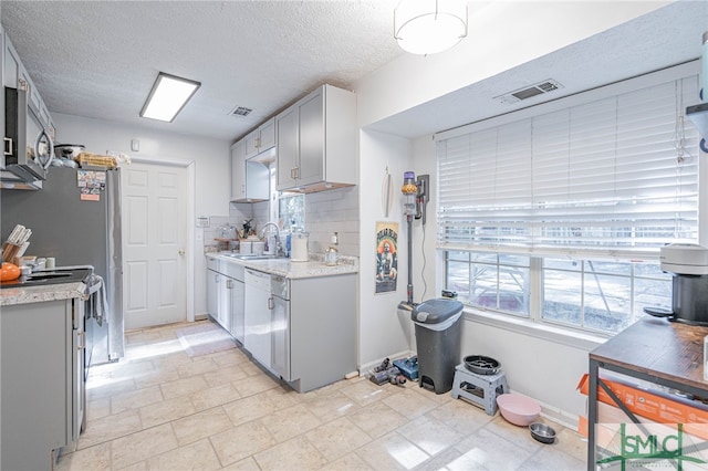 kitchen featuring a textured ceiling, tasteful backsplash, visible vents, and a sink