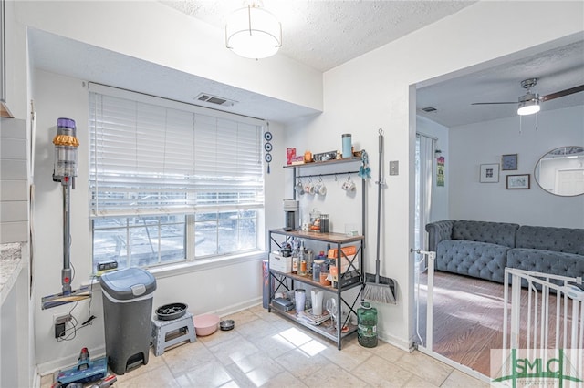 interior space featuring visible vents, baseboards, a textured ceiling, and ceiling fan