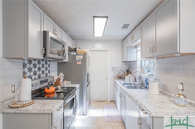 kitchen featuring visible vents, light countertops, stainless steel appliances, a textured ceiling, and a sink