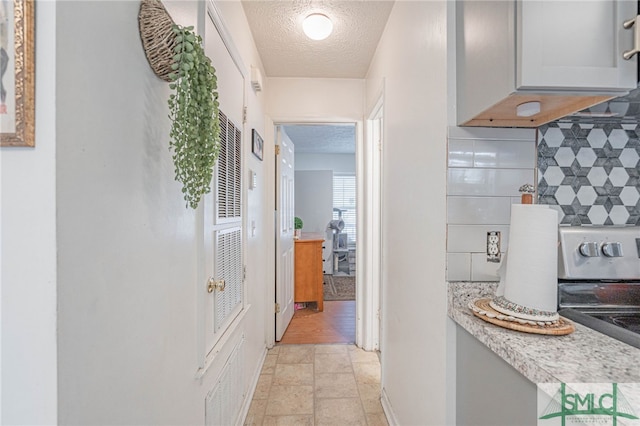 hall featuring stone finish flooring, baseboards, and a textured ceiling