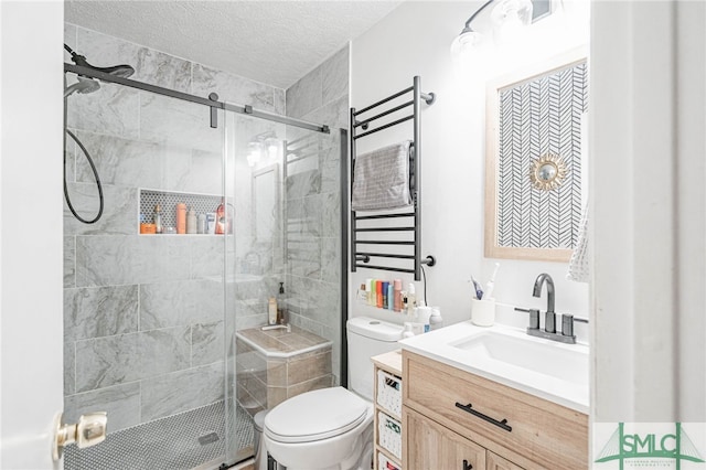 full bathroom featuring a stall shower, toilet, vanity, and a textured ceiling