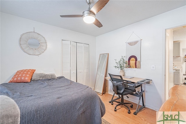 bedroom with light wood finished floors, baseboards, a ceiling fan, and a closet