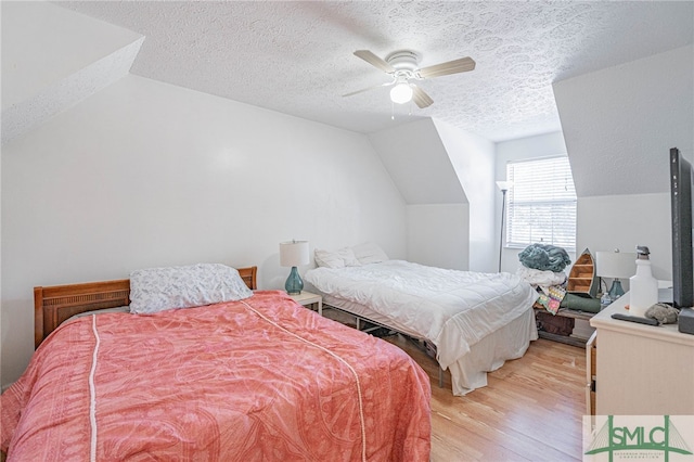 bedroom featuring ceiling fan, lofted ceiling, a textured ceiling, and light wood-style flooring