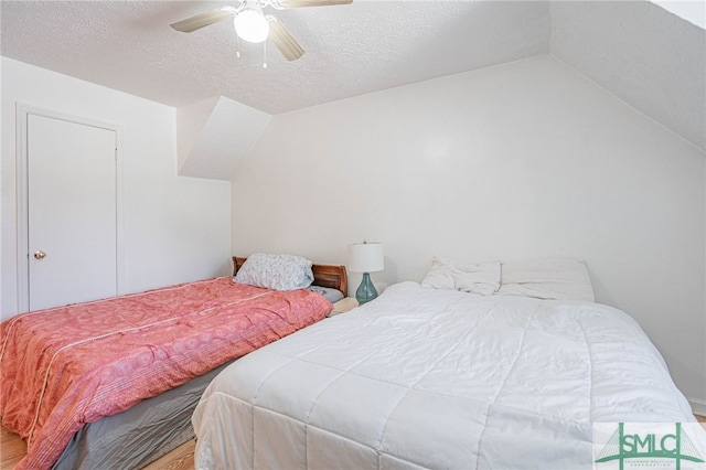 bedroom featuring vaulted ceiling, a ceiling fan, and a textured ceiling