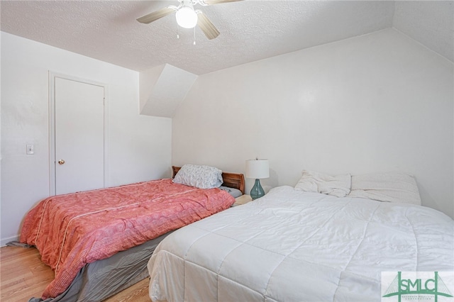 bedroom featuring a textured ceiling, a ceiling fan, lofted ceiling, and wood finished floors