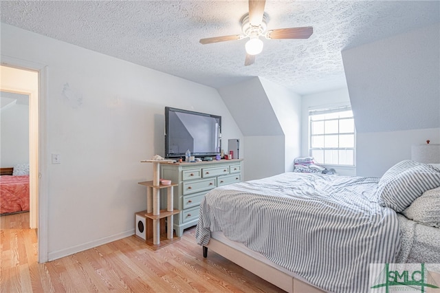 bedroom with baseboards, vaulted ceiling, light wood-style flooring, a textured ceiling, and a ceiling fan