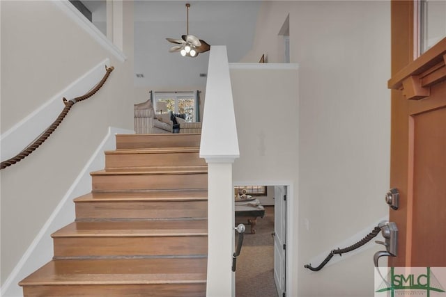 staircase with carpet flooring, a ceiling fan, and a towering ceiling