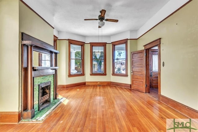 unfurnished living room with light wood-type flooring, baseboards, ceiling fan, and a fireplace