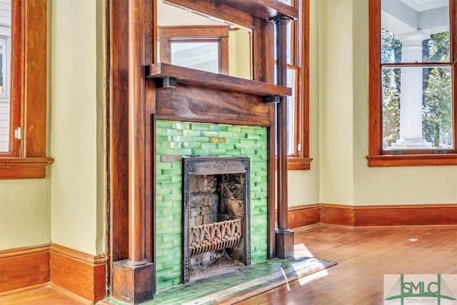 room details with baseboards, a brick fireplace, and wood finished floors