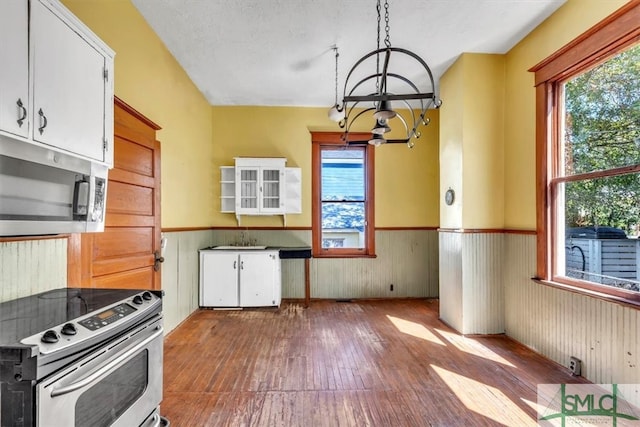 kitchen with stainless steel appliances, a healthy amount of sunlight, a chandelier, and wainscoting