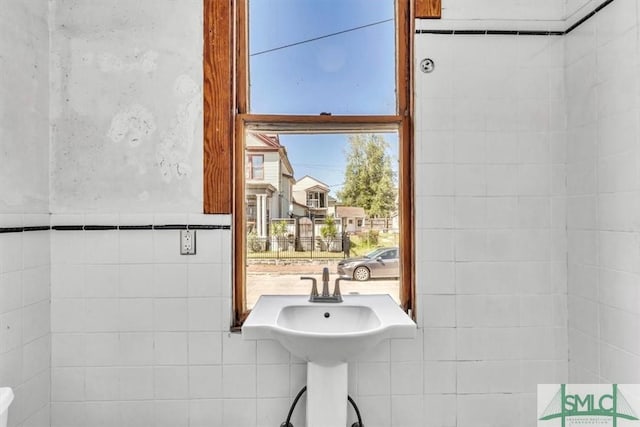 bathroom featuring tile walls, a residential view, and a sink