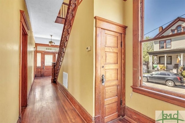 corridor with visible vents, baseboards, hardwood / wood-style floors, and stairs