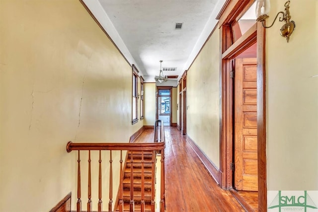 hall featuring visible vents, baseboards, wood finished floors, and stairway