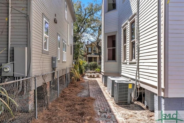 view of side of property with cooling unit and fence