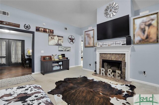 carpeted living area featuring visible vents, a fireplace, and baseboards