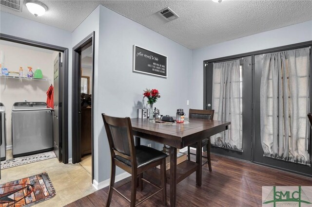 dining space with washer and dryer, light wood-style flooring, visible vents, and a textured ceiling