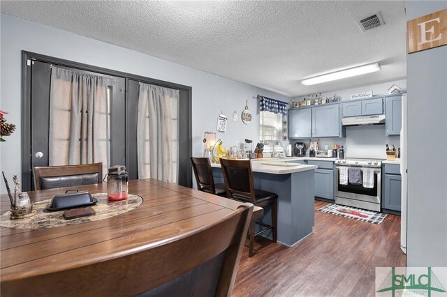 kitchen featuring visible vents, under cabinet range hood, dark wood finished floors, stainless steel electric range oven, and light countertops