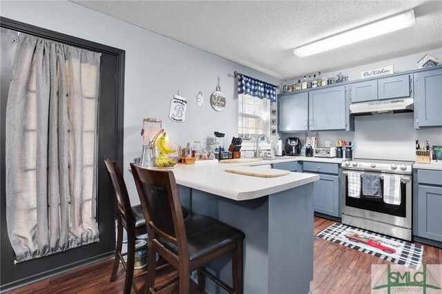 kitchen with a peninsula, dark wood-style floors, under cabinet range hood, and stainless steel range with electric cooktop